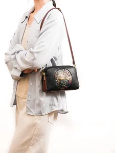 Detail of vintage crossbody bag with embossed elephant pattern and lychee leather texture