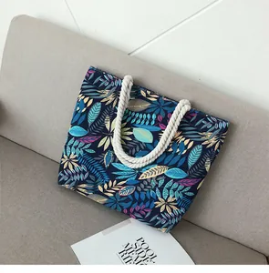 Détail d'un grand sac en toile bleue à imprimés feuilles et poignées en corde de coton blanc