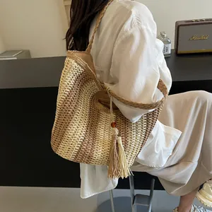 Borsa tote in paglia a righe con nappina decorativa indossata da modella in bianco
