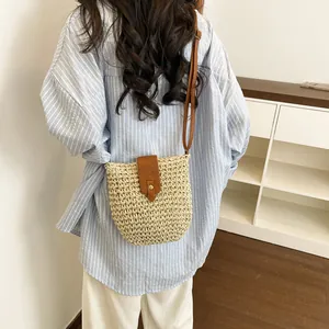 Woven straw crossbody bag with brown leather flap shown in a lifestyle vacation setting