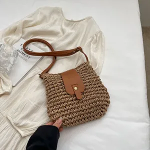 Détail du sac bandoulière en paille tissée avec rabat en cuir marron et sangle réglable