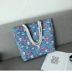 Détail du sac cabas en toile bleue avec motifs hiboux et poignées en coton blanc