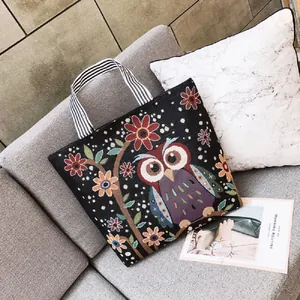 Borsa tote in tela stile etnico con ricamo a gufo colorato e manici a righe sul divano
