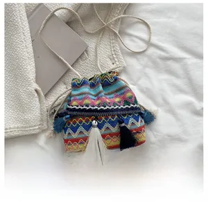 Détail d'un sac seau bohème tissé avec motifs géométriques colorés et longues franges