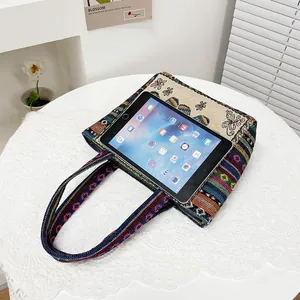 Borsa etnica ricamata con farfalle in lino e cotone, mostrata con un tablet piatto