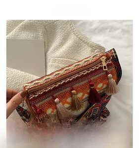 Macro view of woven cylinder bag featuring colorful tassels and ethnic geometric patterns