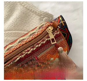 Close-up of bohemian cylindrical bag with colorful embroidery and red tassel detail