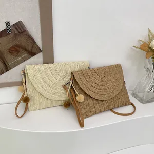 Woven straw envelope crossbody bag with decorative pom-poms in cream and brown
