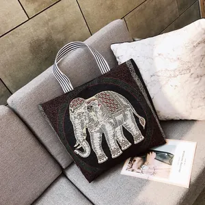 Borsa tote etnica con motivo a elefante ricamato e manici a righe su un divano