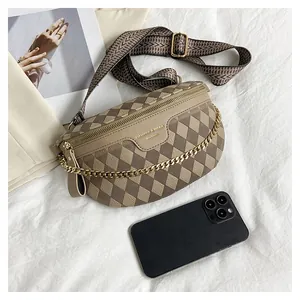 Detail view of khaki quilted chest bag with woven strap, chain and phone for size scale
