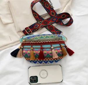 Detail view of ethnic embroidery crossbody bag with colorful tassels and woven strap