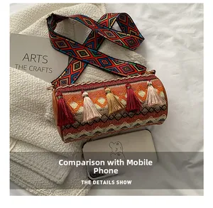 Detailed shot of cylinder woven bag with tassels and wide strap showing phone size fit