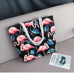 Détail du sac cabas en toile avec imprimé flamant rose et anses en corde sur canapé