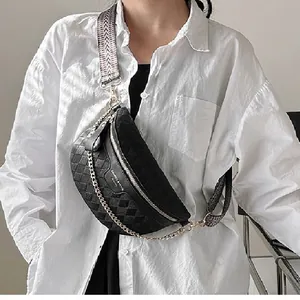 Quilted black waist bag with gold chain and woven strap worn across a white shirt