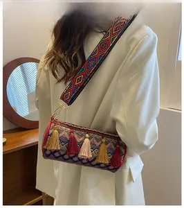 Detail of bohemian cylinder bag featuring ethnic jacquard weave and vibrant tassel accents