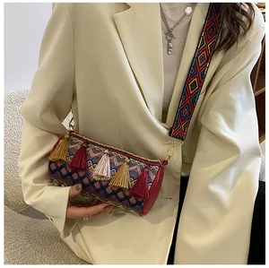 Detail of bohemian cylinder bag featuring colorful tassel charms and woven geometric patterns