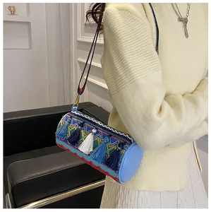 Detailed close-up of Bohemian woven cylinder bag with colorful embroidery and tassels