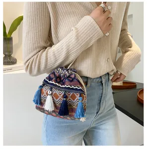 Détail du sac seau bohème avec tissage coloré et pompons dégradés sur le côté du sac