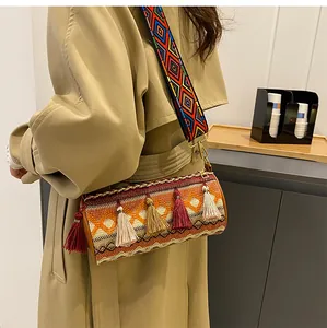 Detailed view of bohemian woven cylinder bag with colorful tassels and embroidered strap