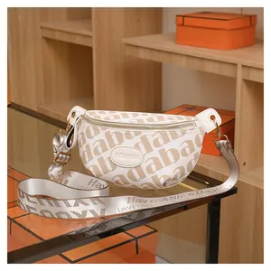 Detail view of the cream-colored crossbody bag featuring brown logo prints and texture