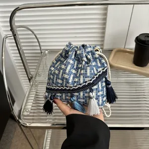 Détail du sac seau en tweed bleu et blanc avec longues franges et cordon de serrage