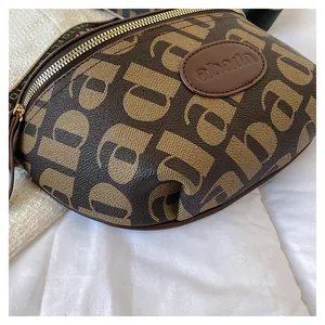Detail of brown leather chest bag showing monogram pattern and golden zipper finish