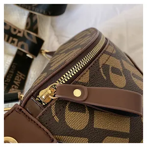 Macro detail of brown leather bag with golden zipper and printed nylon strap