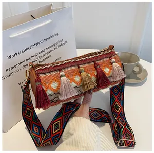 Detail of bohemian woven cylindrical bag with colorful tassels and ethnic wide strap