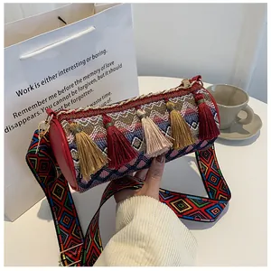Detail of bohemian woven cylinder bag with colorful tassels and patterned wide strap