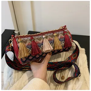 Detail of bohemian cylindrical bag with colorful tassels and wide jacquard strap