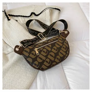 Detail of adjustable wide strap and gold zipper on a brown letter print chest bag