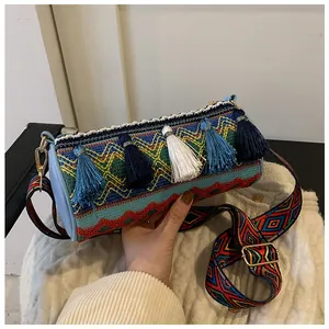 Detail of bohemian woven cylindrical bag featuring colorful tassels and wide shoulder strap