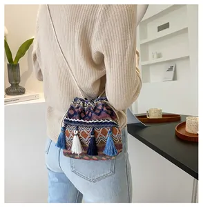 Détail du sac seau bohème avec motifs géométriques tricotés et pompons bleus