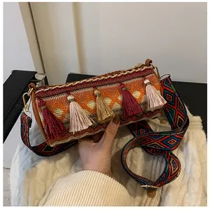 Detail of bohemian cylinder bag with colorful tassels and geometric woven wide strap