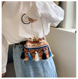 Détail du sac seau tissé aux motifs géométriques avec des pompons bleus décoratifs