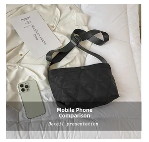 Close-up of black quilted shoulder bag with smartphone for size comparison