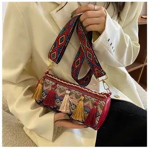 Detail of bohemian cylinder bag with colorful woven patterns and long fringe tassels