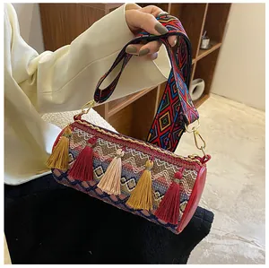 Detail view of woven cylinder bag with colorful tassels and geometric ethnic strap