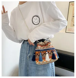 Détail du sac seau tissé bohème avec motifs géométriques et longs ornements à glands