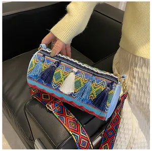 Detail of colorful woven cylindrical bag with decorative tassels and wide patterned strap