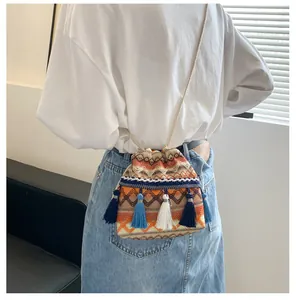 Détail du sac seau tissé ethnique avec motifs à vagues et pompons épais suspendus