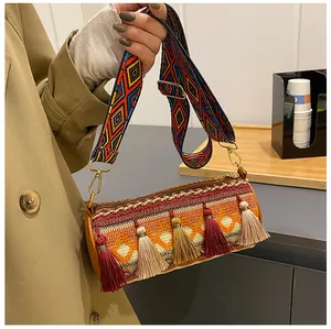 Detail of bohemian cylindrical bag featuring ethnic embroidery and colorful tassels