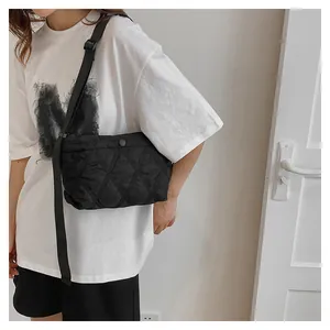 Detail of black quilted shoulder bag featuring classic rhombic texture and round snap button