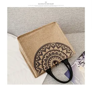 Detalle del bolso tote grande de yute con diseño étnico y asas de cincha negras