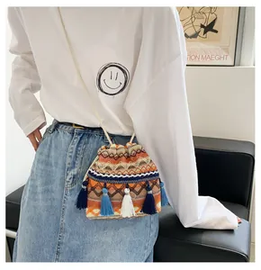 Sac seau bohème tissé avec glands et motifs géométriques colorés sur une tenue décontractée