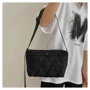 Detail of black quilted crossbody bag showing nylon texture and adjustable strap