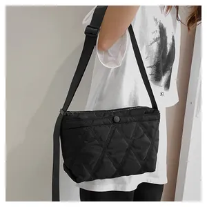 Close-up of quilted black nylon texture and secure zipper closure on shoulder bag