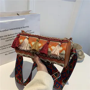 Ethnic woven cylinder crossbody bag with colorful tassels and wide geometric strap