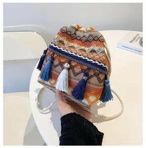Détail d'un sac seau tissé bohème avec glands colorés et motifs de vagues géométriques