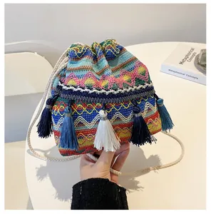 Vue détaillée du sac seau tissé ethnique avec motifs géométriques colorés et pompons